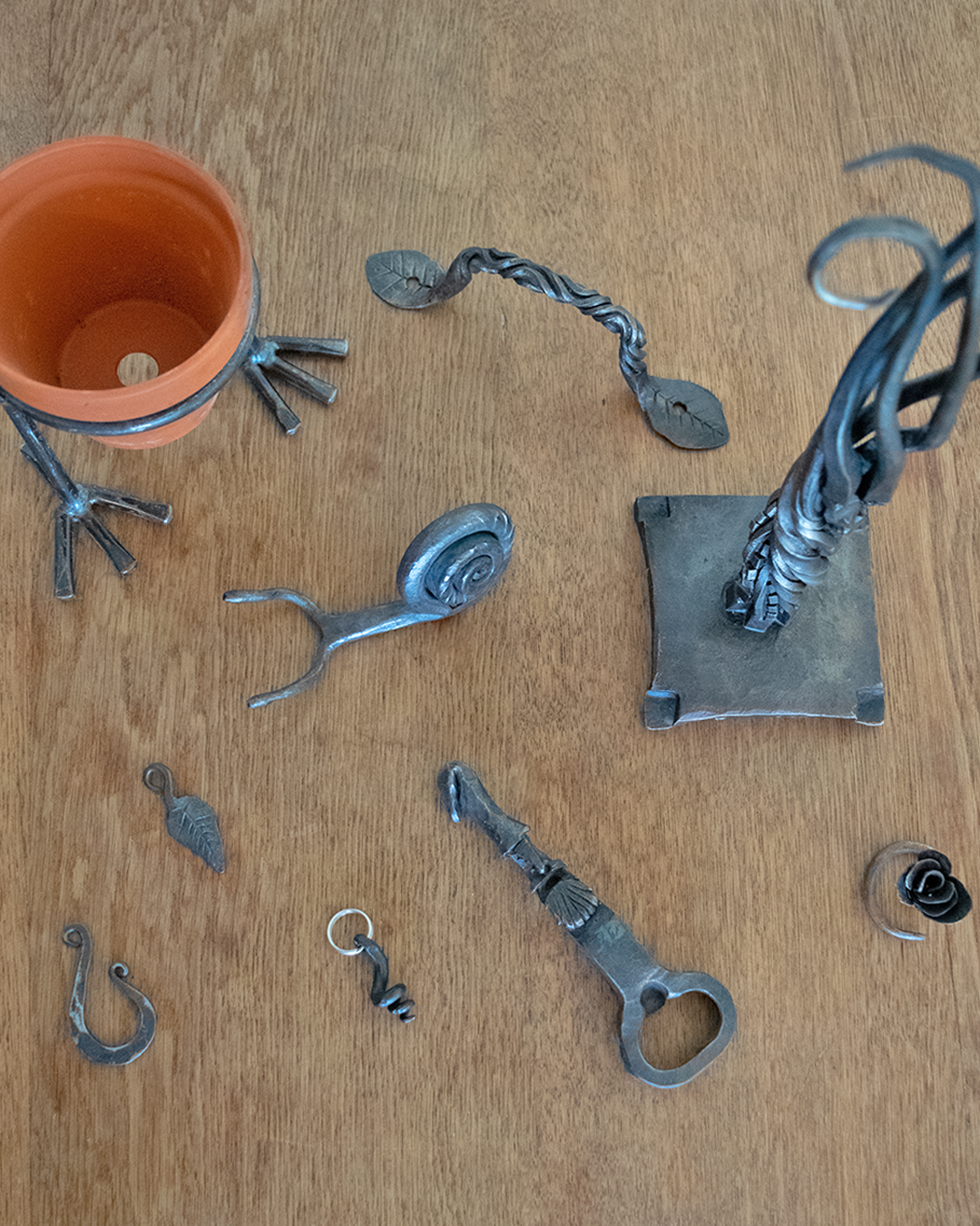 Collection of handcrafted metalwork pieces including plant holders, decorative items, and functional art